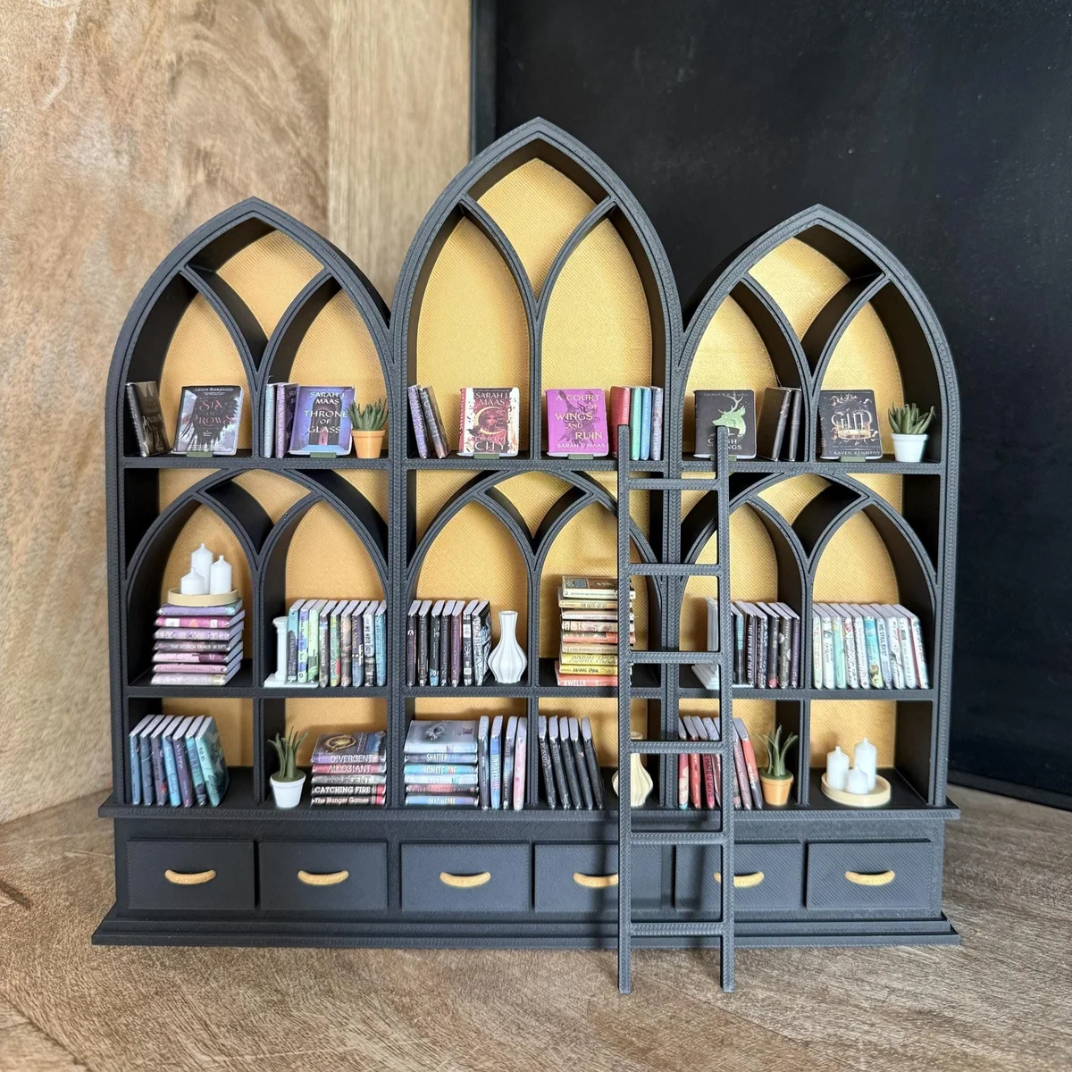 Gothic miniature library bookcase in black with gold interior, styled in a dollhouse room with books and accessories, 1:12 scale